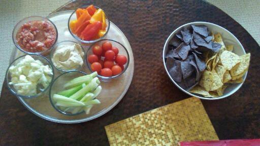 Image of a plate of cut up vegetables on the left and a bowl of corn chips on the right